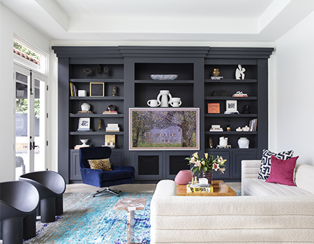 Family room with large arched french doors on the left, whole wall built ins and a large custom L couch in Houston, TX